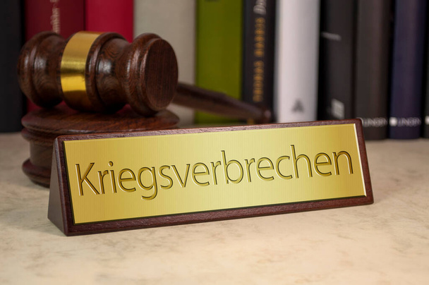 Gavel and law book with sign and the german word for war crimes - Kriegsverbrechen on a wooden table - Фото, изображение