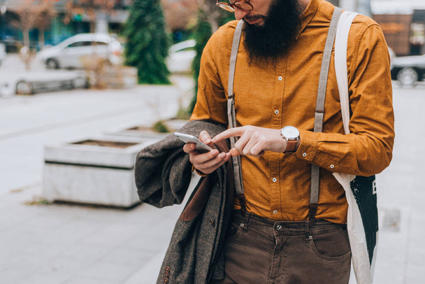 Young caucasian guy clothed in a fashionable costume using a mobile phone - Foto, Imagem