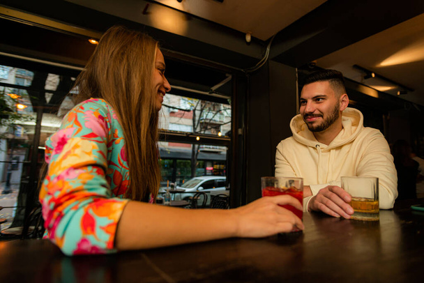 Attractive and handsome guy is having a conversation with his girl on the bar while sitting - Photo, Image