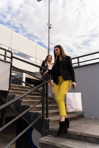 Two amazing and attractive businesswomen are walking down the stairs together while thinking - 写真・画像