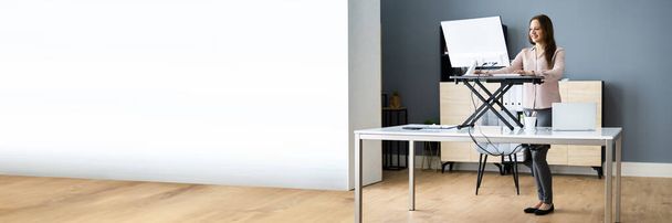 Adjustable Height Desk Stand In Office Using Computer - Foto, imagen