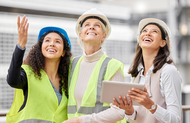 Конечный продукт. Обрезанный снимок трех привлекательных женщин-инженеров с помощью планшета во время работы на строительной площадке. - Фото, изображение