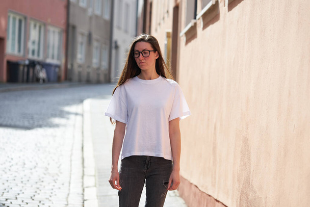 Woman in white blank t-shirt wearing glasses in the city - 写真・画像