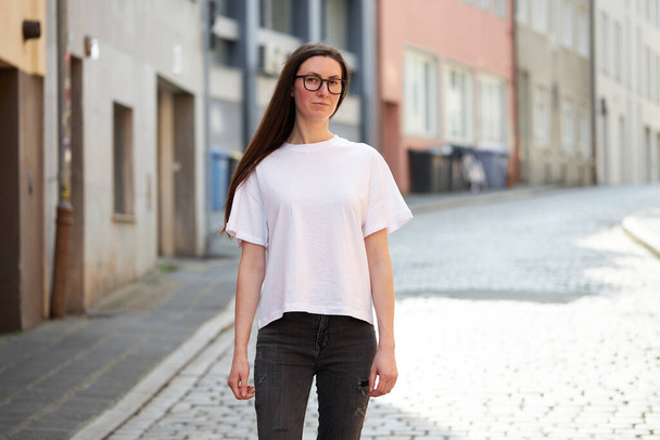 Woman in white blank t-shirt wearing glasses in the city - Zdjęcie, obraz