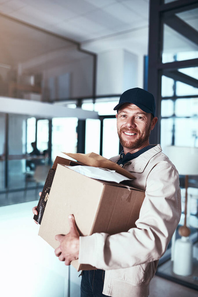 These guys are getting a new home. Portrait of a cheerful young man holding two boxes inside of a office building during the day. - Foto, Bild