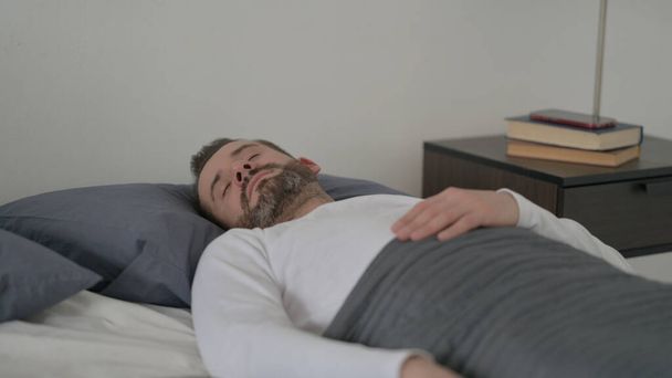 Ο άνθρωπος κοιμάται στο κρεβάτι γαλήνια - Φωτογραφία, εικόνα