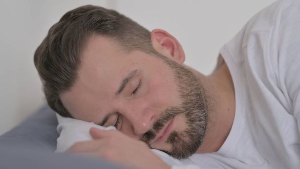 Ο άνθρωπος κοιμάται στο κρεβάτι γαλήνια - Φωτογραφία, εικόνα