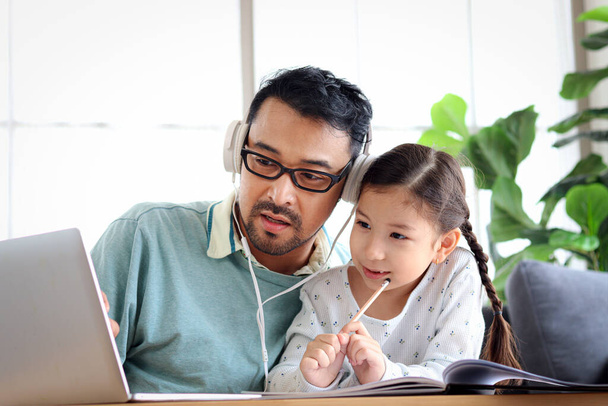 Young handsome father teach adorable girl daughter to do school homework, using laptop computer for e-learning study at home, dad and kid spend time together for education and searching Internet. - Photo, Image