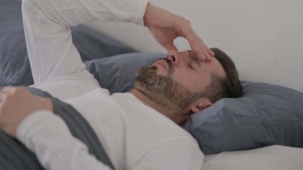 Ο άνθρωπος έχει πονοκέφαλο ενώ κοιμάται στο κρεβάτι - Φωτογραφία, εικόνα