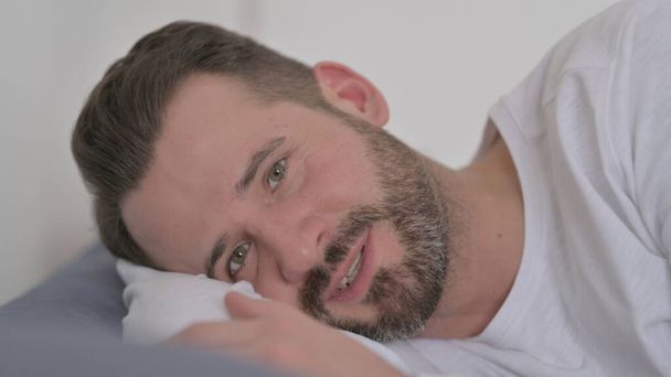 Hombre hablando en videollamada mientras está acostado en la cama - Foto, Imagen