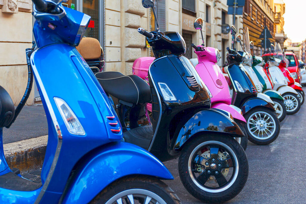 Серия разноцветных мотороллеров Веспа, припаркованных подряд вдоль улицы, место аренды скутера в городе. - Фото, изображение