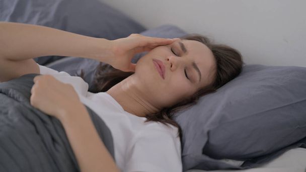Woman having Headache while Sleeping in Bed - 写真・画像