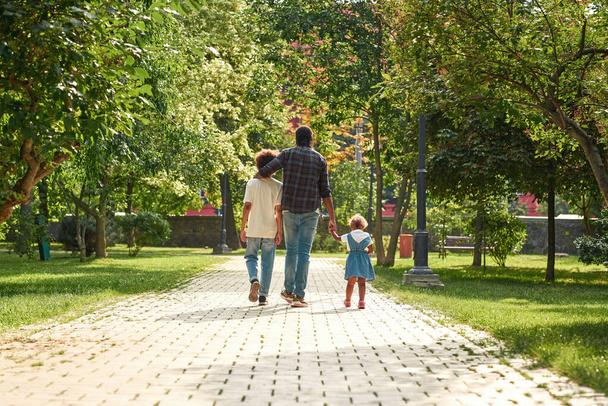 Father with children walk on pavement road in park - Photo, image