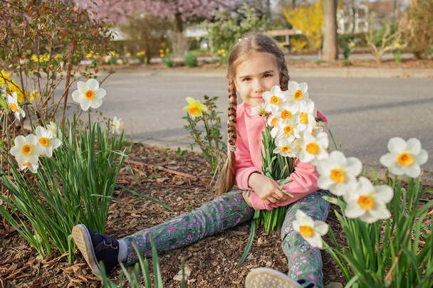 Tyttö vaaleanpunainen huppari haisee kukkiva haara narcissus aikana hänen kävely keväällä puutarhassa - Valokuva, kuva