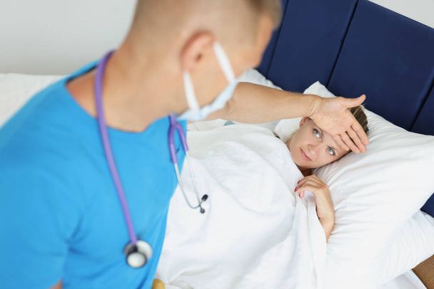 Lekarz dotyka czoła chorej kobiety w łóżku - Zdjęcie, obraz