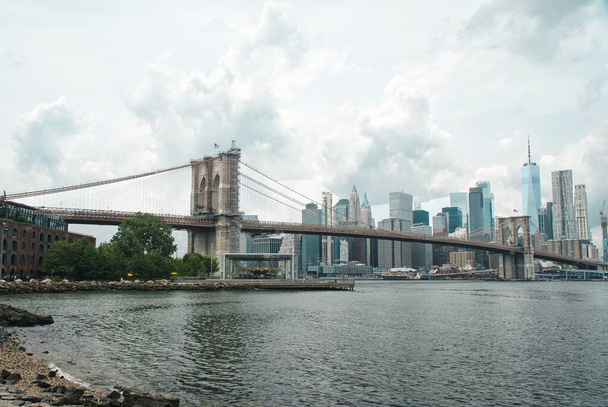 ニューヨークの曇りの日にマンハッタンのスカイラインとブルックリン橋のパノラマビュー. - 写真・画像