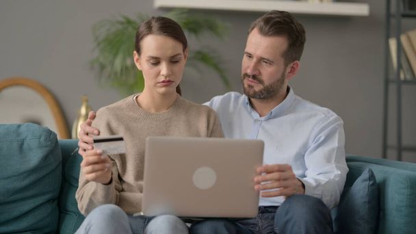 Couple having Successful Online Shopping on Laptop on Sofa  - Foto, afbeelding