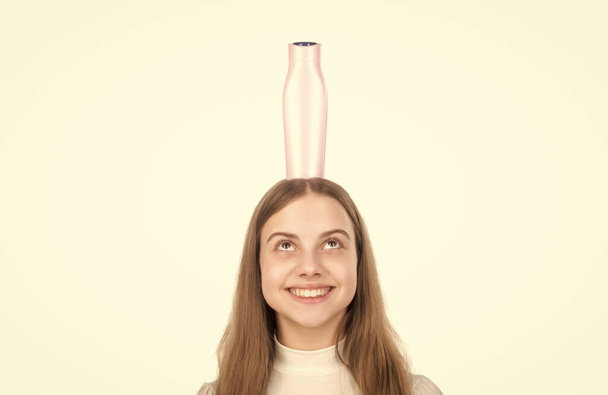 szczęśliwy nastolatek dziewczyna prezentuje szampon lub włosy odżywka do ciała butelka izolowana na biały, fryzjer - Zdjęcie, obraz