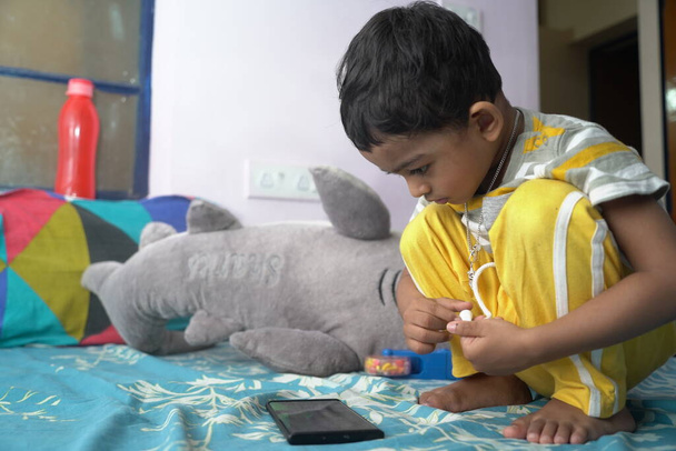 un niño pequeño niño dedicado a ver y explorar el teléfono móvil.Imagen del concepto de adicción al tiempo de pantalla - Foto, imagen