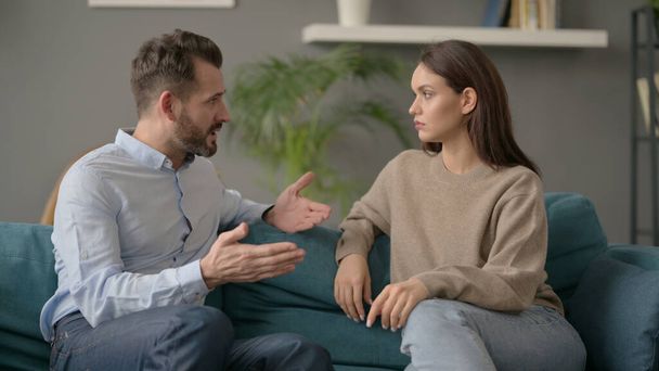 Seriöser Mann spricht Frau an, während er auf Sofa sitzt  - Foto, Bild