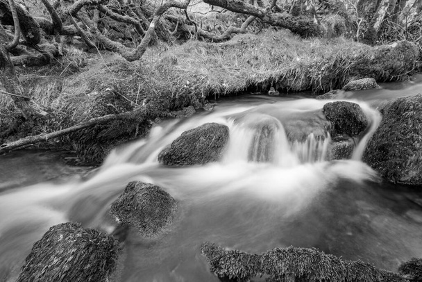 Larga exposición del río Weir Water que fluye a través del valle en el puente Robbers en el Parque Nacional Exmoor - Foto, imagen