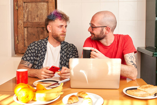 Пара геїв на кухні снідають з ноутбуком
 - Фото, зображення