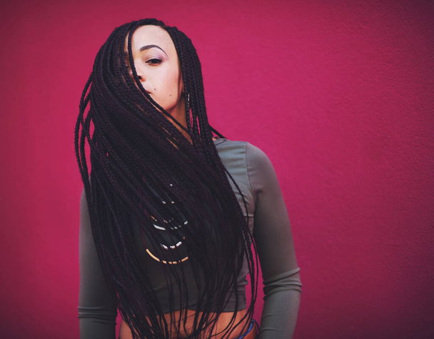 Style is the art of being yourself. Shot of a young woman with braids posing against a pink background. - Foto, Imagem