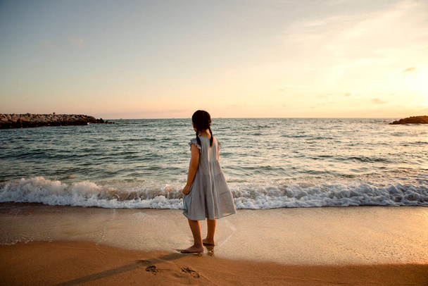 girl children standing at sea beach against beautiful sunset light - Фото, изображение