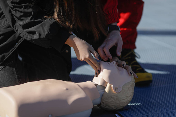 Details with the hands of a female student learning how to perform cardiopulmonary resuscitation (CPR) on a mannequin for educational purposes. - Фото, изображение