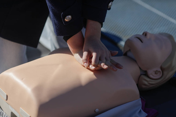 Details with the hands of a female student learning how to perform cardiopulmonary resuscitation (CPR) on a mannequin for educational purposes. - Zdjęcie, obraz