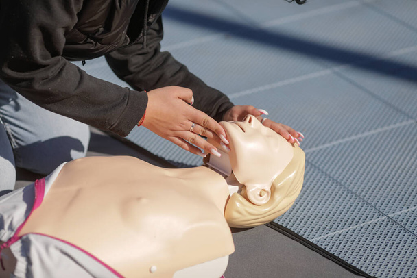 Detalles con las manos de una estudiante que aprende a realizar reanimación cardiopulmonar (RCP) en un maniquí con fines educativos. - Foto, imagen