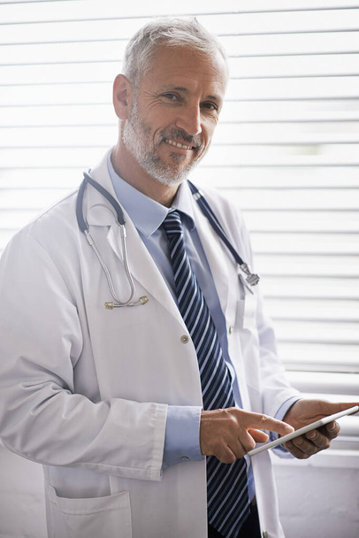Tüm hasta kayıtlarıma hızlı ve kolay erişim. Dijital tablet kullanan olgun bir erkek doktorun portresi. - Fotoğraf, Görsel
