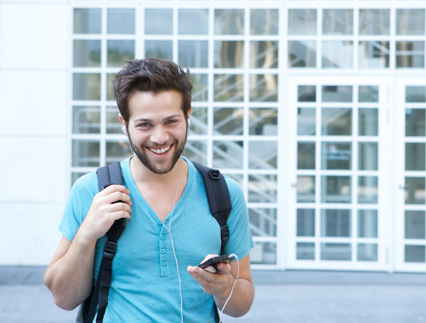 Smiling young man with mobile phone and backpack - Fotografie, Obrázek