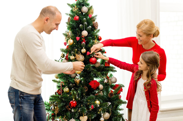 Lächelnde Familie schmückt Weihnachtsbaum zu Hause - Foto, Bild