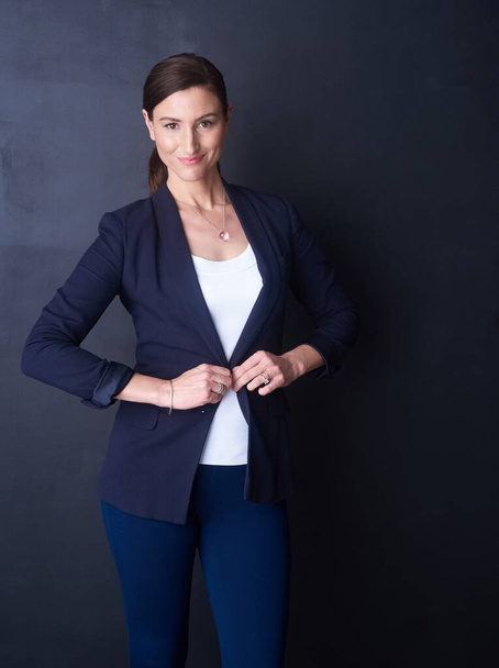 Dress smart, act smarter. Portrait of a happy businesswoman posing against a dark background in the studio. - Фото, зображення