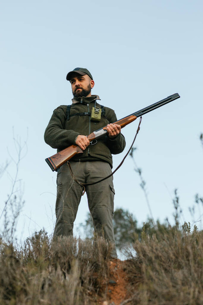 Man with gun hunting in countryside in clear day - Photo, Image