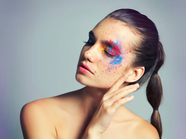 Makeup meets art. Studio shot of an attractive young woman with brightly colored makeup against a gray background. - Fotografie, Obrázek
