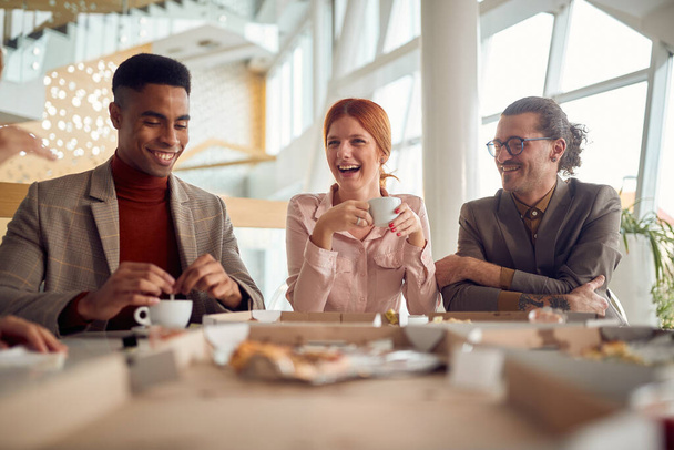 Una joven mujer de negocios alegre y sus colegas masculinos están de muy buen humor durante una pausa para almorzar en un ambiente alegre en el edificio de la compañía. Negocios, gente, empresa - Foto, Imagen