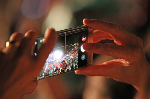 mujer toma una película con teléfono inteligente durante el concierto en vivo con muchos espectadores - Foto, imagen