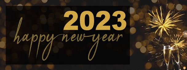 HAPPY NEW YEAR 2023 - Festive silvester background panorama banner long - Golden yellow firework and champagne classes toasting on black night texture with bokeh lights - Photo, Image