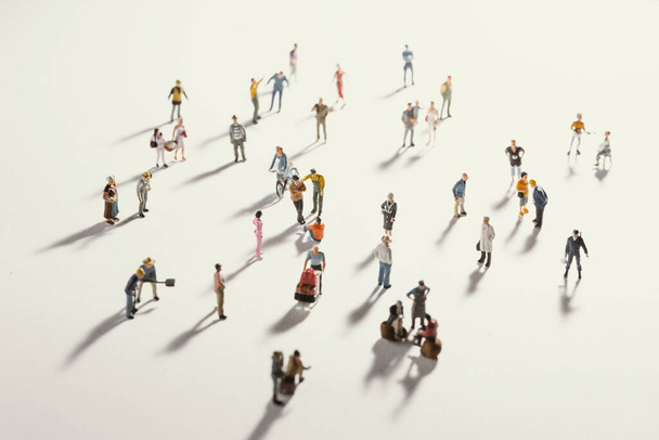 Top view of people (miniature toys) with long shadows keep distance away in public during sunrise or sunset.Social distancing during COVID-19 coronavirus outbreak spreading concept. - Photo, Image