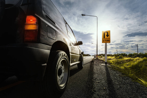 Parada de coche SUV negro en la carretera de asfalto y esperar a que el giro en U con borroso signo de giro en U en larga distancia. - Foto, Imagen