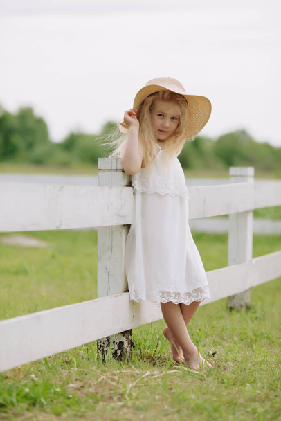 Beautiful little blonde girl on a ranch on a summer day. - Photo, image