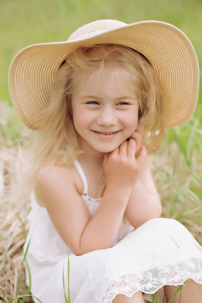 Portrait of a shy little blonde on a ranch on a summer day. - Photo, Image