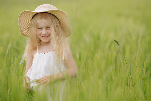 Liebenswertes kleines Mädchen spielt an einem warmen Sommertag im Weizenfeld - Foto, Bild