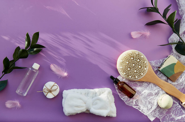 Hygiene accessories, natural soap, essence oil, massage brush, bath bomb, sponges on purple background. SPA beauty treatment. Shadows, copy space. - Foto, afbeelding