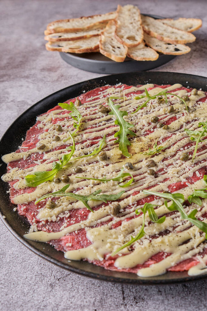 黒プレート上のパルメザンチーズ、ケッパーとアルグラとビーフカルパッチョ冷たい前菜,選択的な焦点 - 写真・画像