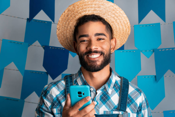 Festa Junina: вечеринка в Бразилии, портрет человека с мобильным телефоном на июньском фестивале в кайпирской одежде - Фото, изображение