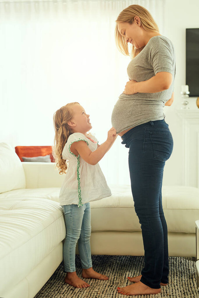 Она не может дождаться, чтобы стать старшей сестрой. Снимок беременной женщины, проводящей время со своей маленькой девочкой. - Фото, изображение