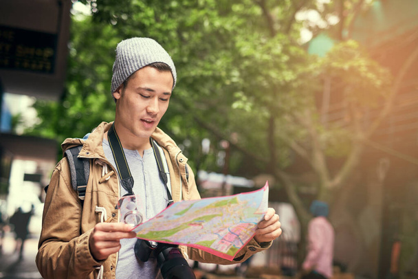 Am I heading in the right direction. Cropped shot of a young man using a map while travelling in the city. - Foto, Bild